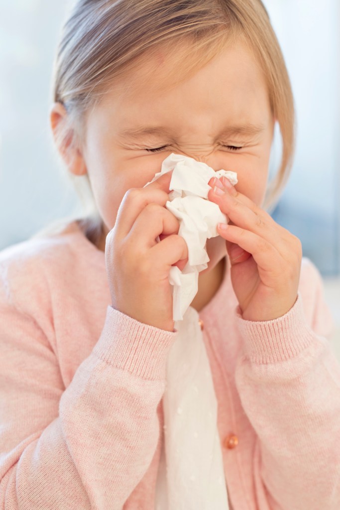 A little girl sneezing. 